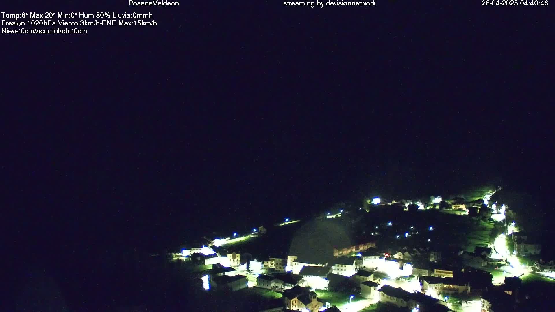 A small, illuminated village sits on a hillside at night under a dark, clear sky.