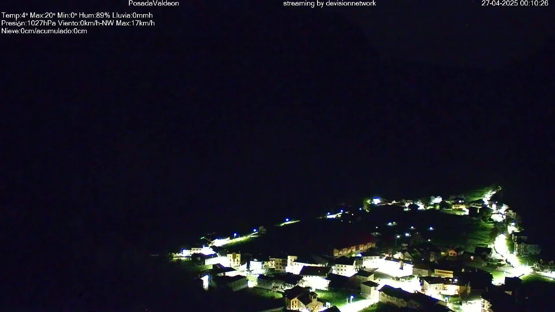 A small, illuminated village nestled in a dark, hilly landscape at night.