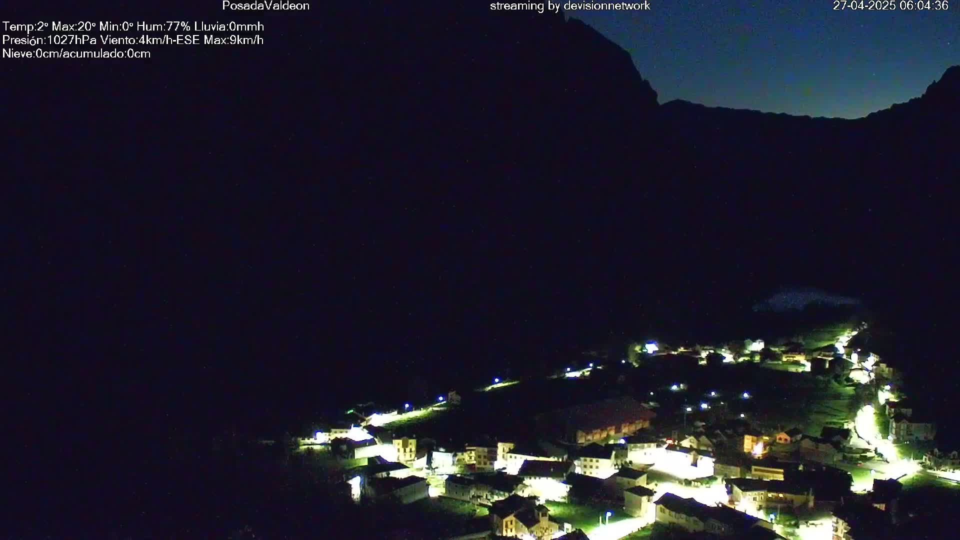 A small, illuminated village nestled in a dark valley under a night sky.