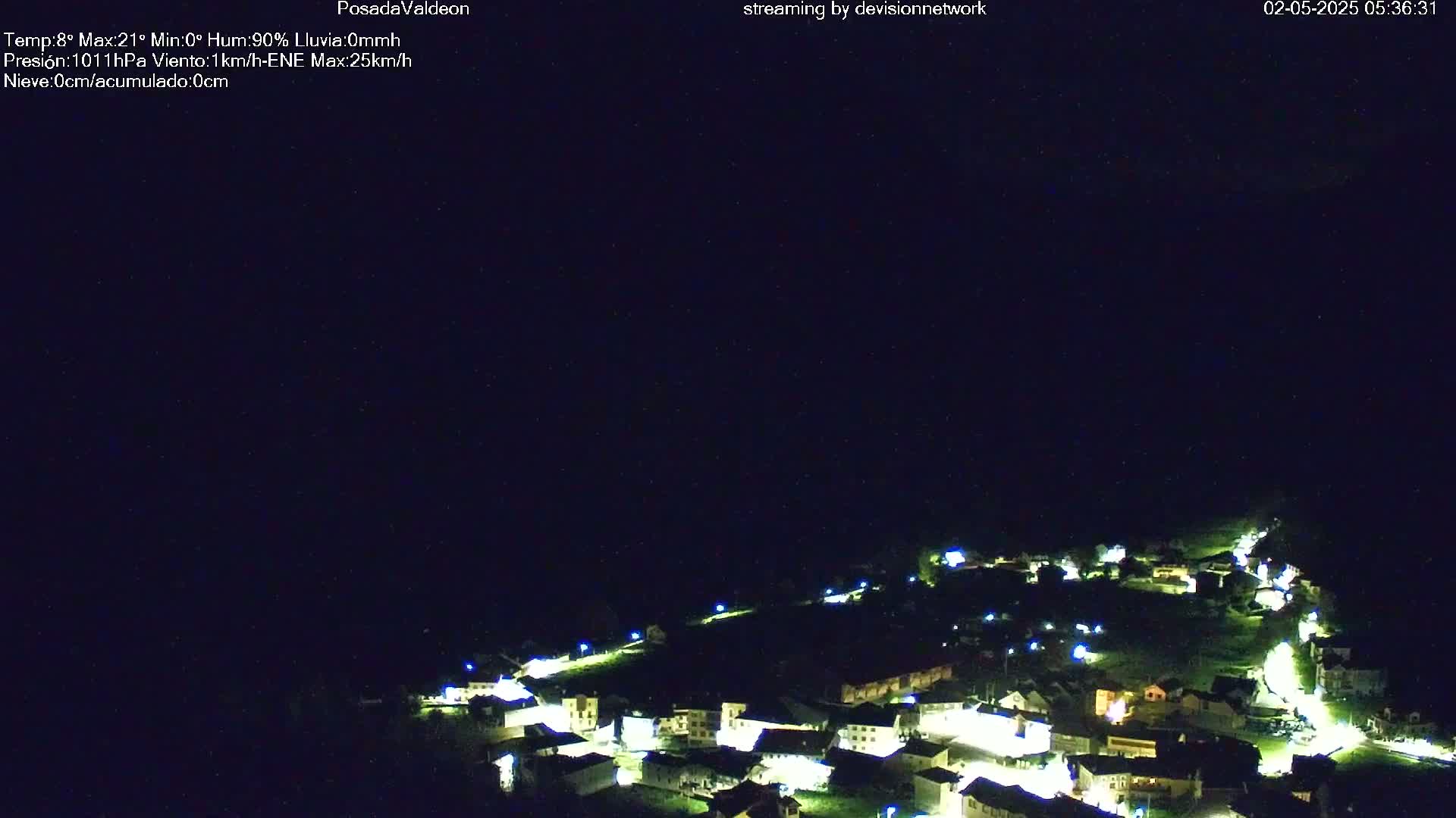A small village at night is illuminated under a dark, clear sky.