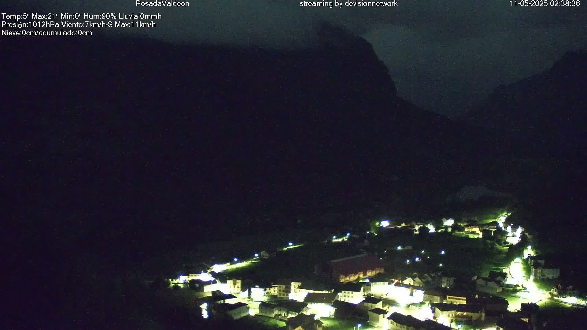 A small, illuminated village nestled in a dark valley under a nighttime sky.