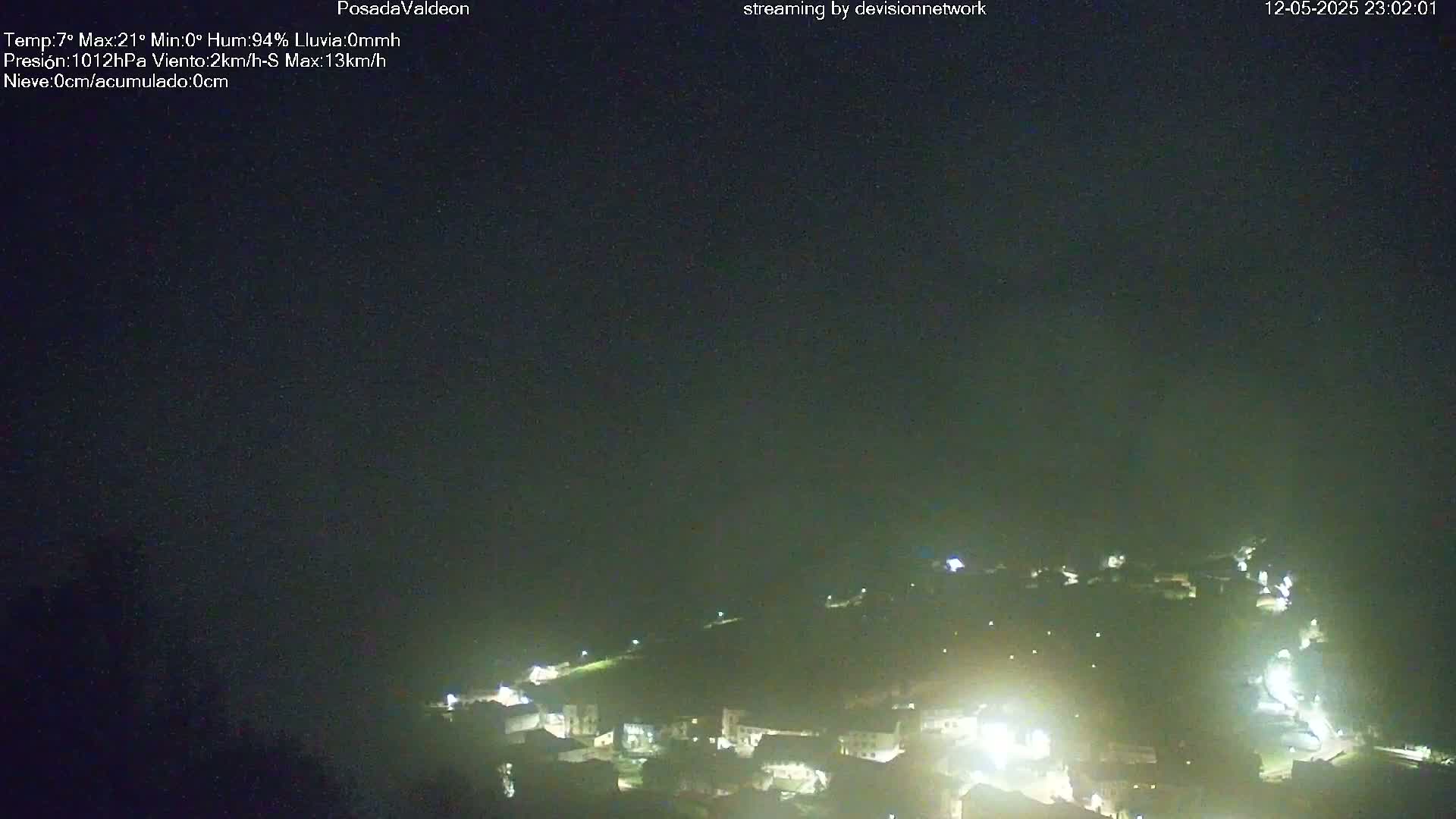 A nighttime, high-angle view of a small town illuminated by lights under a dark, clear sky.