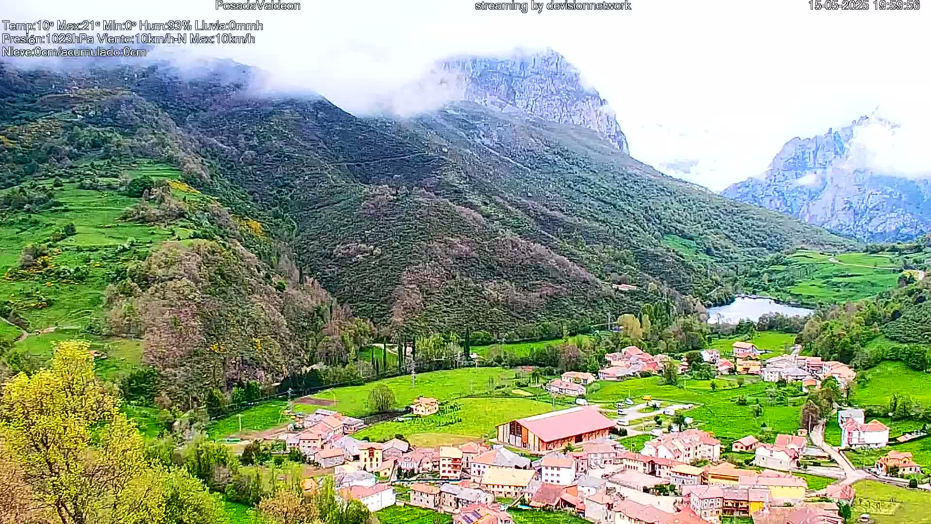 A valley town nestled amongst verdant hills and mountains partially shrouded in mist.