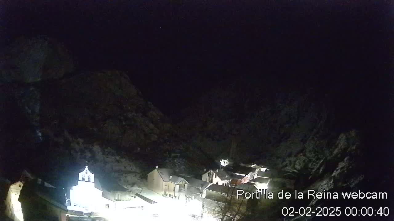 A small, snow-covered village nestled in a valley between dark mountains under a clear night sky.