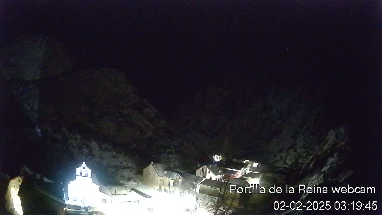 A snow-covered village nestled in a dark, mountainous area at night.