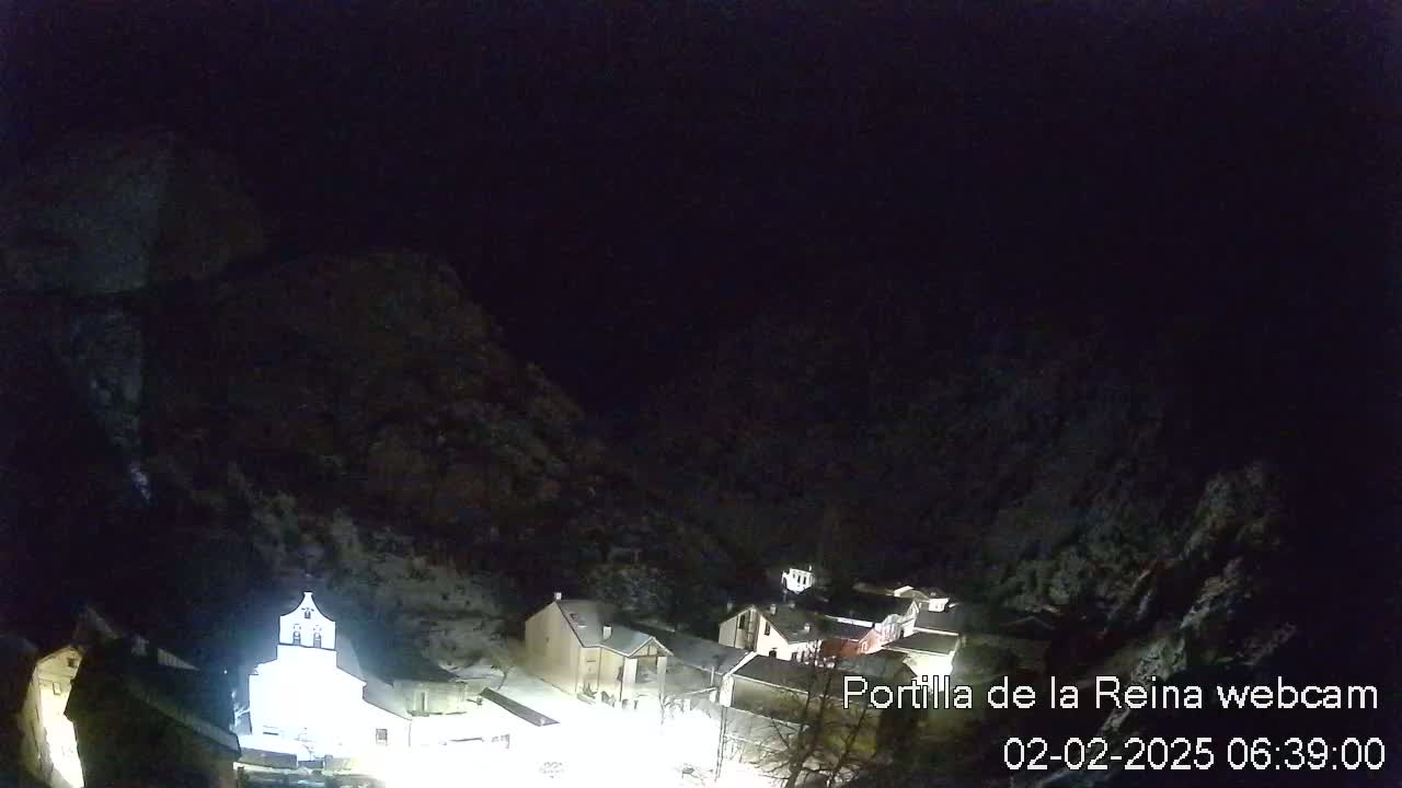 A small, snow-covered village nestled in a dark, mountainous valley at night.