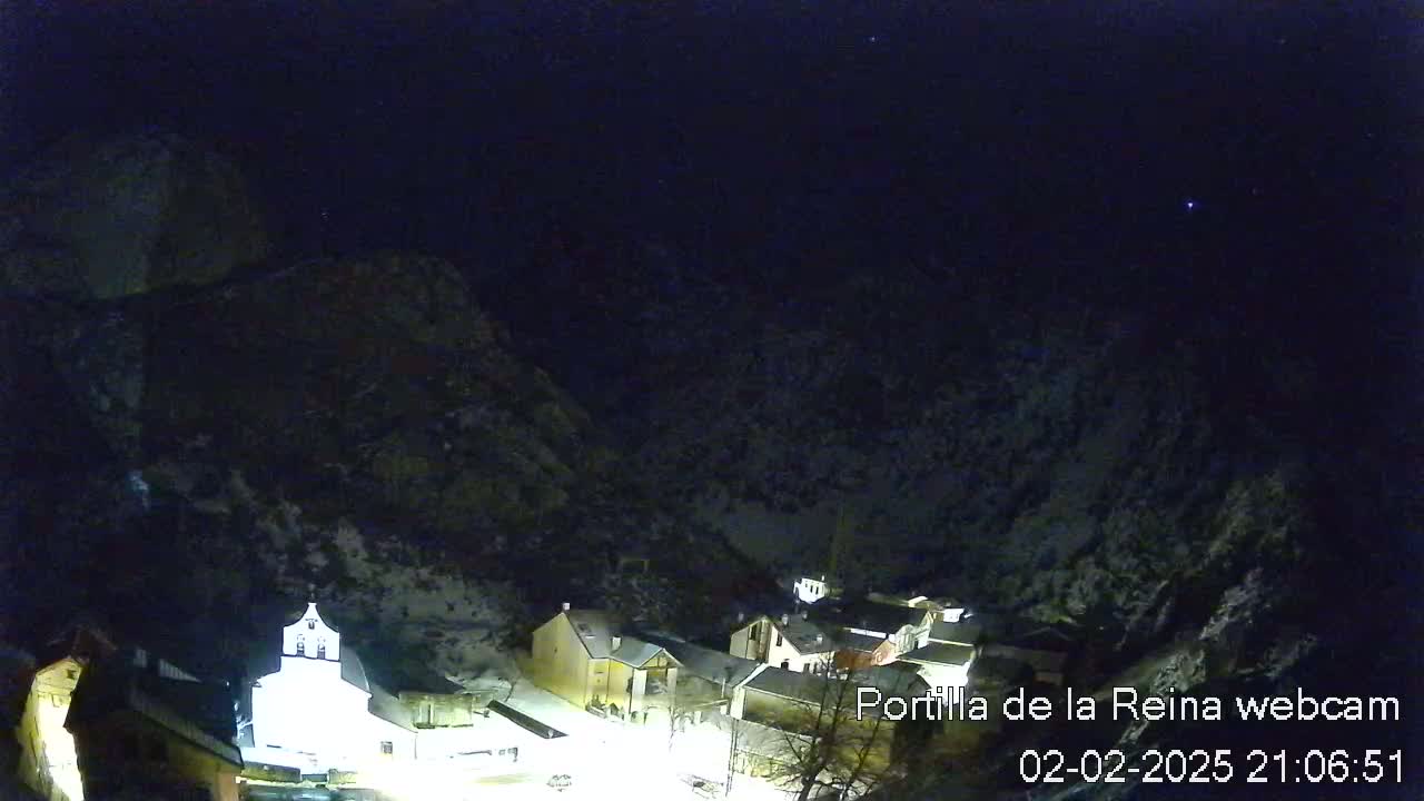 A snow-covered village nestled in a mountainous region at night under a clear, starry sky.