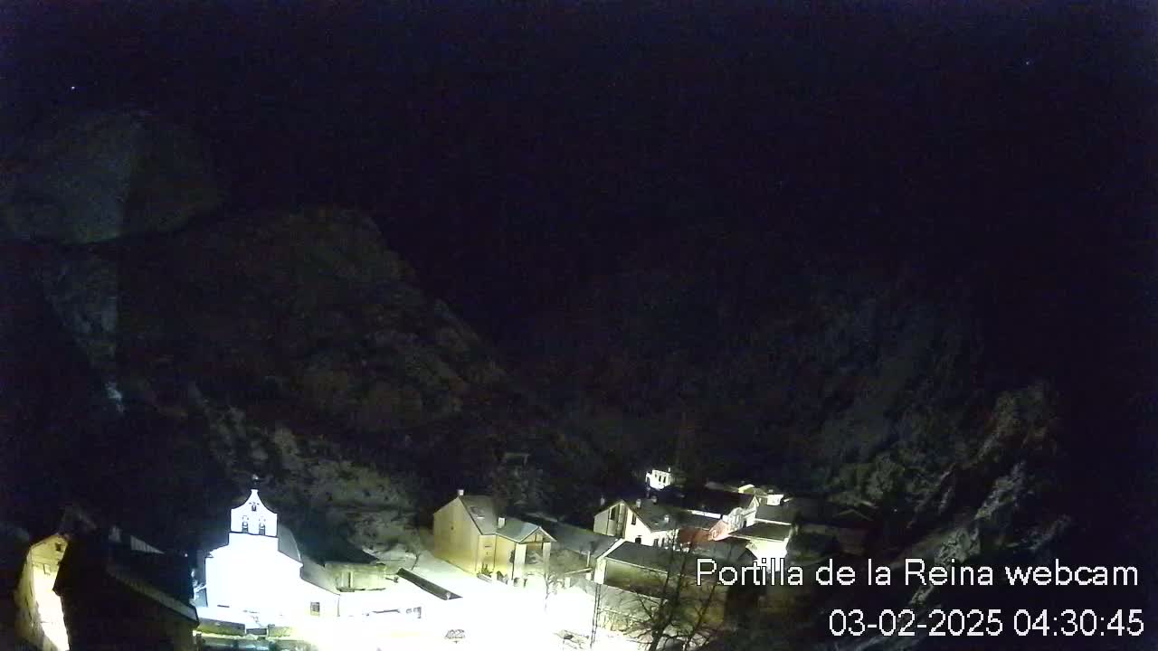 A small, snow-dusted village nestled in a dark, mountainous valley at night.