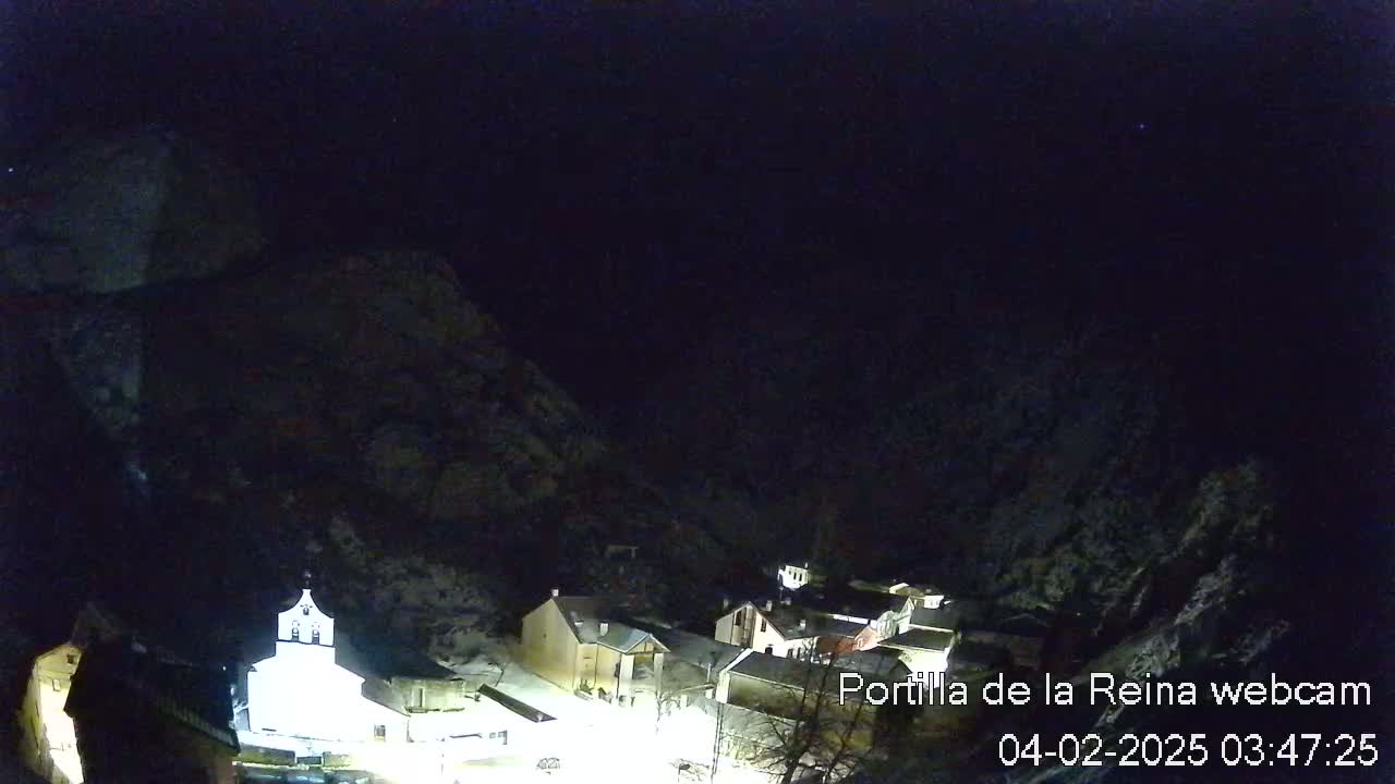 A snow-dusted village nestled in a dark, mountainous area at night.