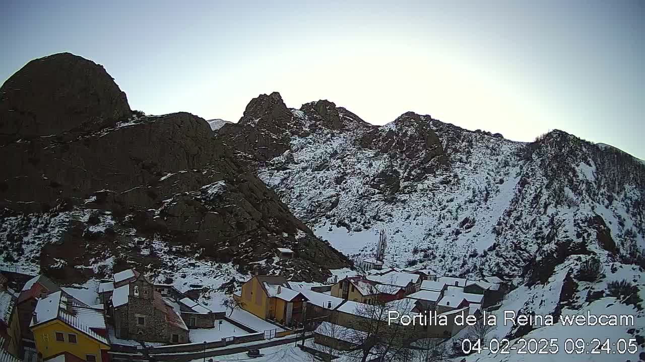 A snow-covered village nestled in a mountainous valley under a clear sky.
