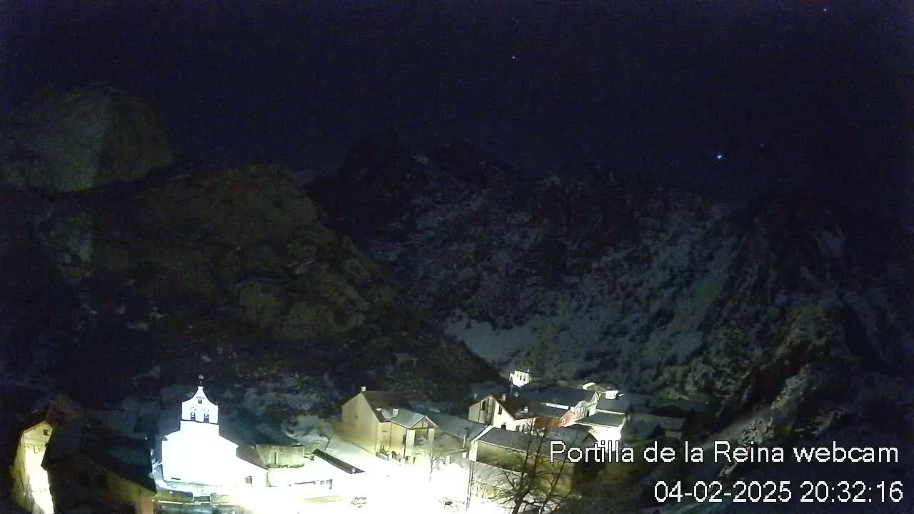 A small, snow-covered village nestled in a valley under a dark, starlit night sky.