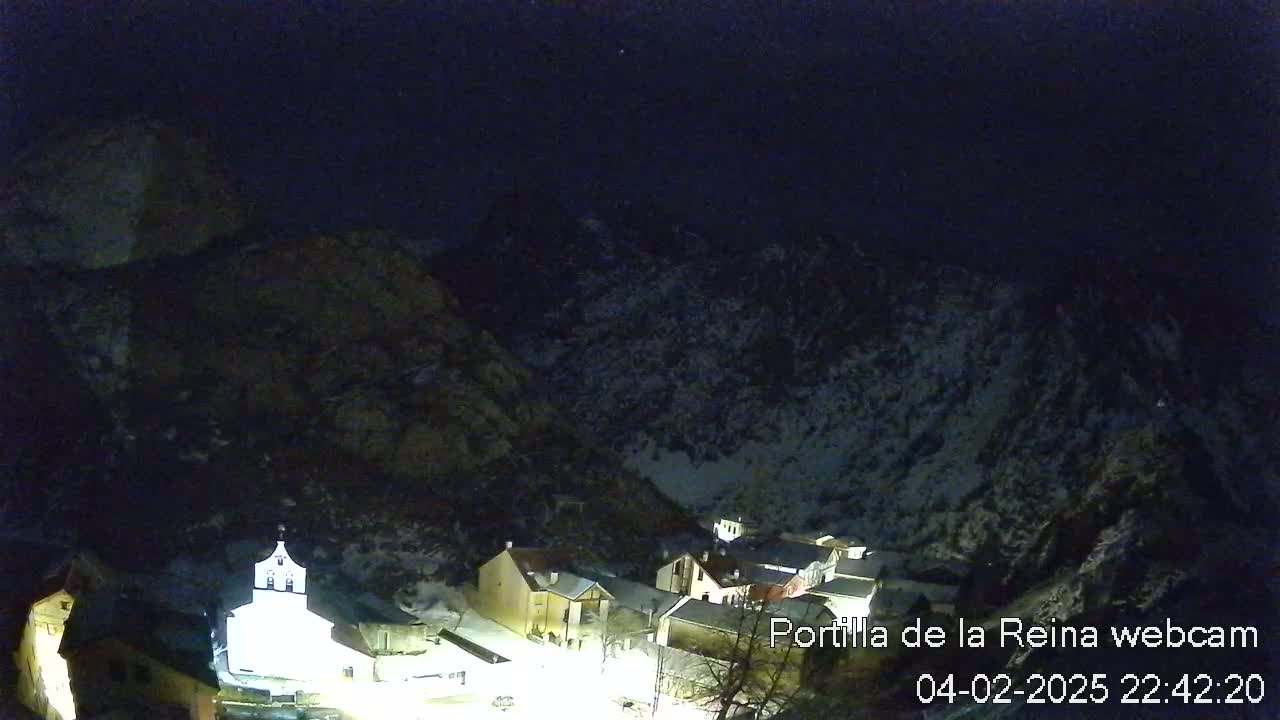 A small, snow-dusted village nestled in a dark, mountainous valley at night.