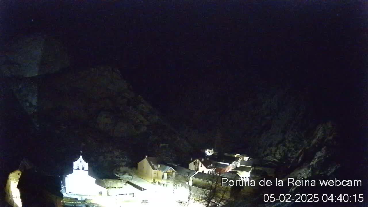 A small village nestled in a mountain valley at night under a clear, dark sky.