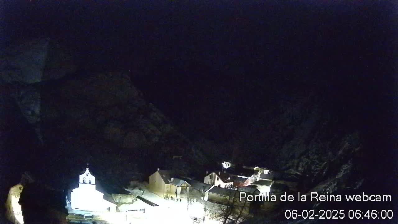 A small, snow-dusted village nestled in a dark, mountainous valley at night.