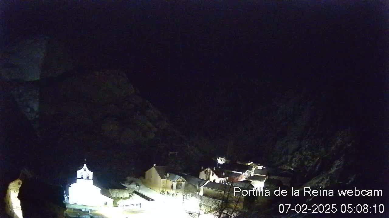 A small, snow-covered village nestled in a dark, mountainous valley at night.