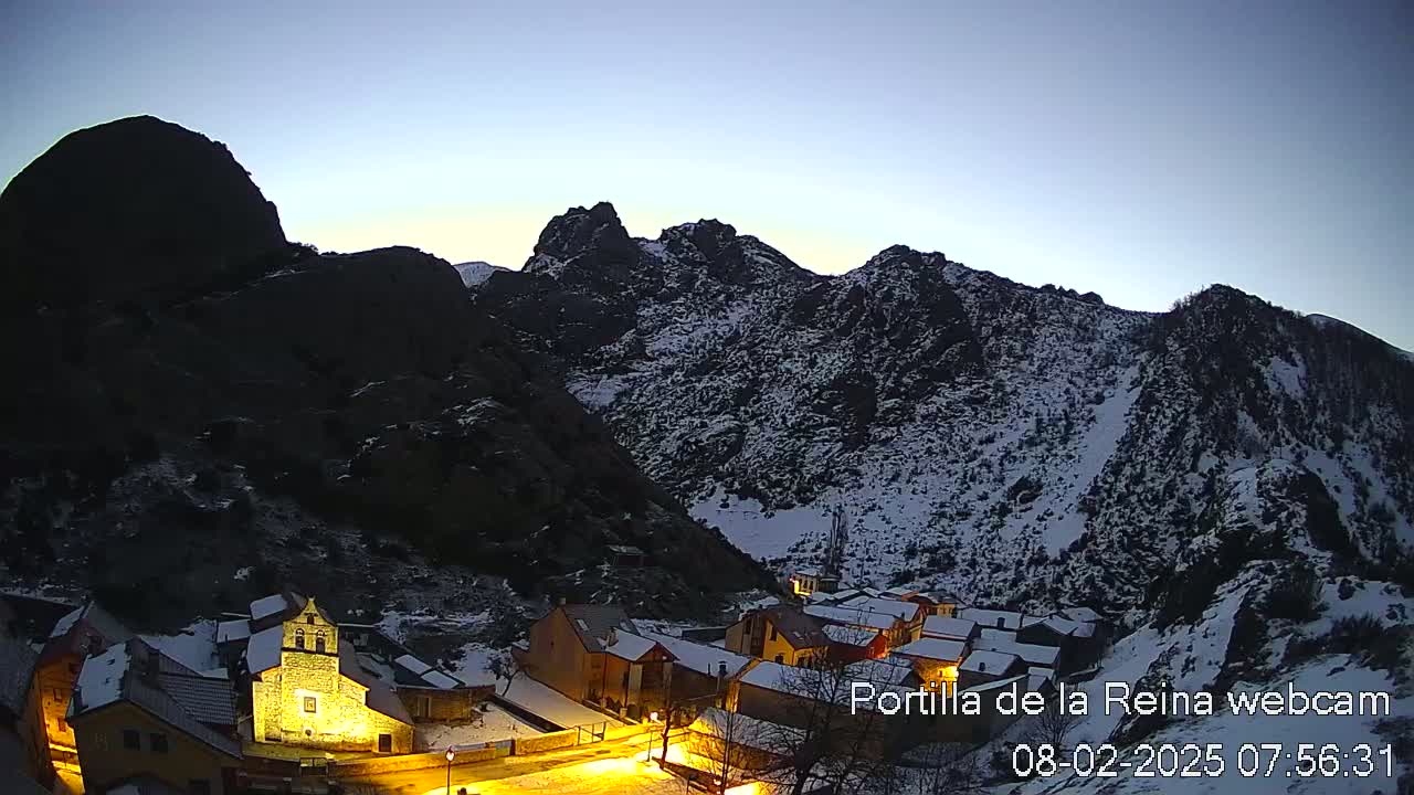 A small village nestled in a snow-dusted mountain valley at twilight.