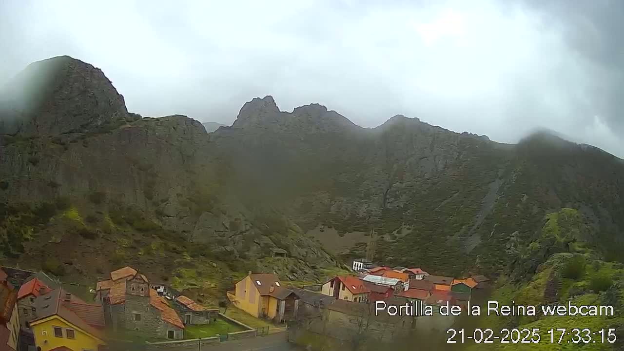 A small village nestled in a valley surrounded by misty, rocky mountains.