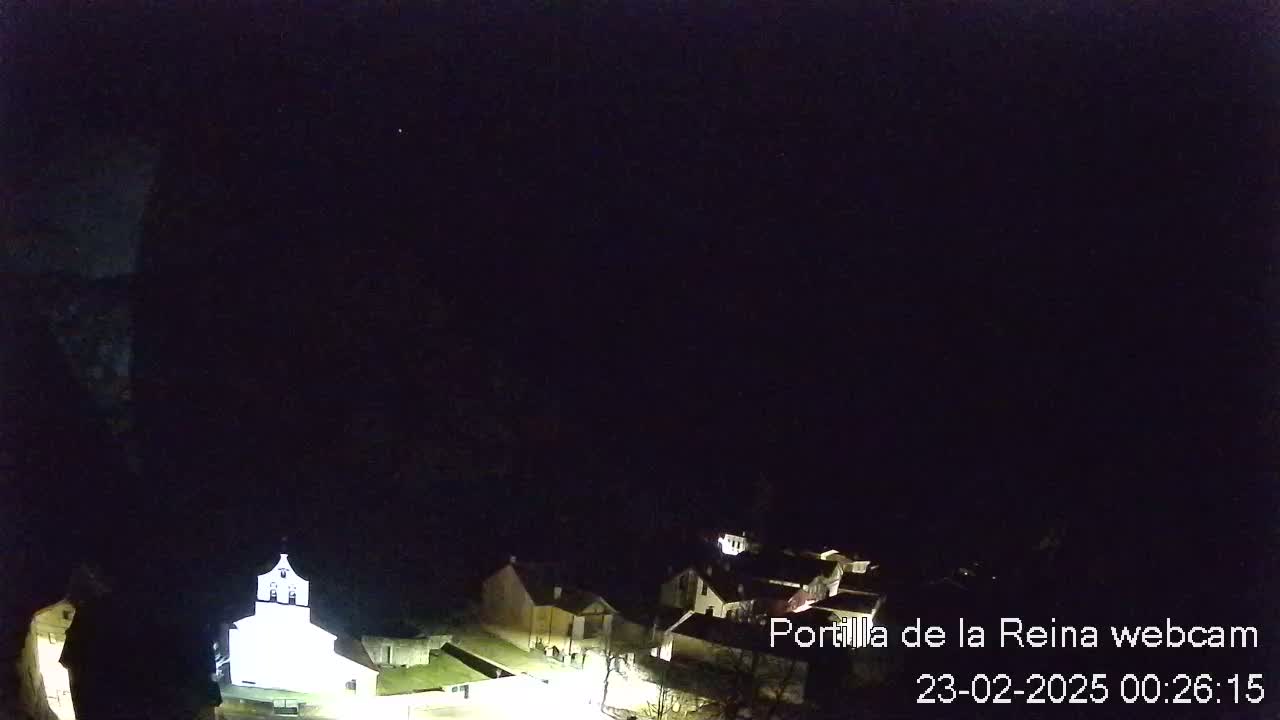 A nighttime, overhead view shows a small village with dimly lit buildings under a dark, clear sky.