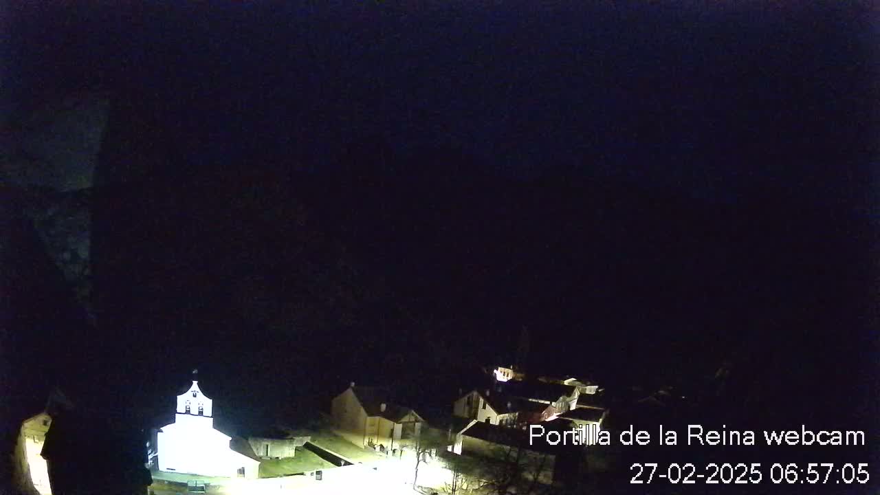 A nighttime view of a small village nestled in a dark, mountainous area.