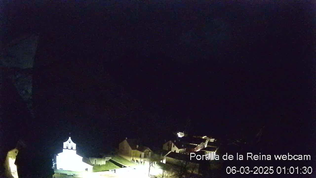 A nighttime, high-angle view shows a small village with a brightly lit church, under a dark sky.