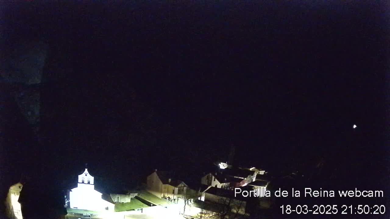 A nighttime view of a small village with dimly lit buildings under a clear, dark sky.