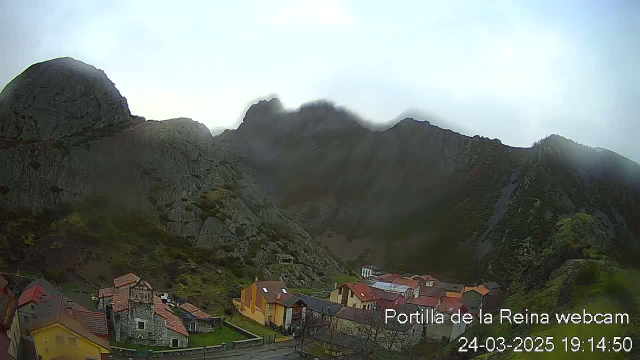 A small village nestled at the base of mist-shrouded mountains.