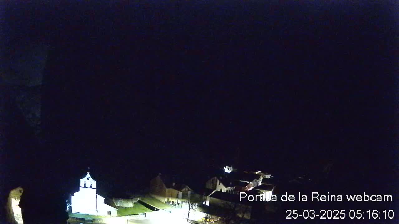A nighttime, aerial view of a small town with a church illuminated, under a dark, clear sky.
