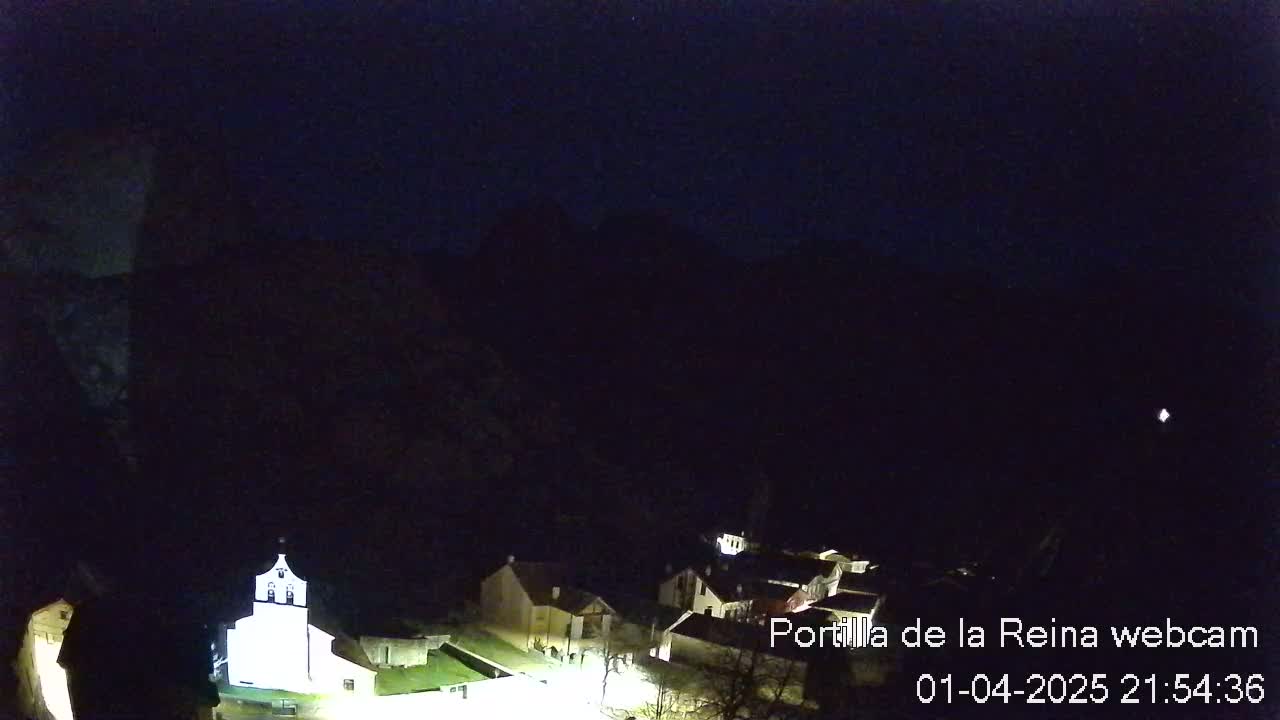 A small, dimly lit village nestled in a dark, mountainous valley at night.