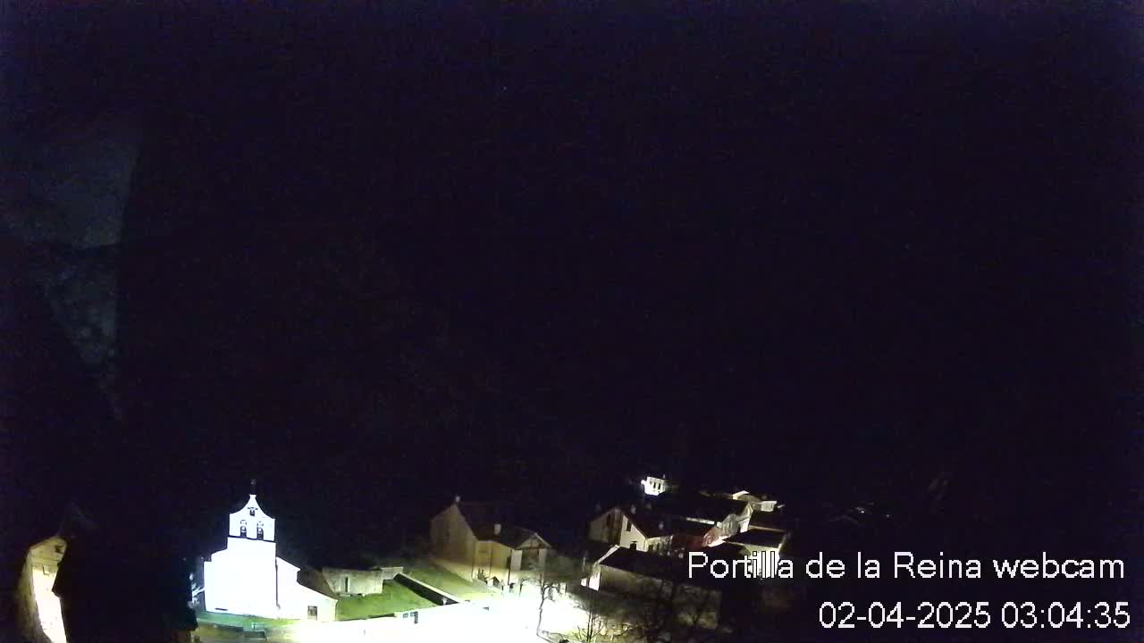 A nighttime view of a small village with a church illuminated, under a dark sky.