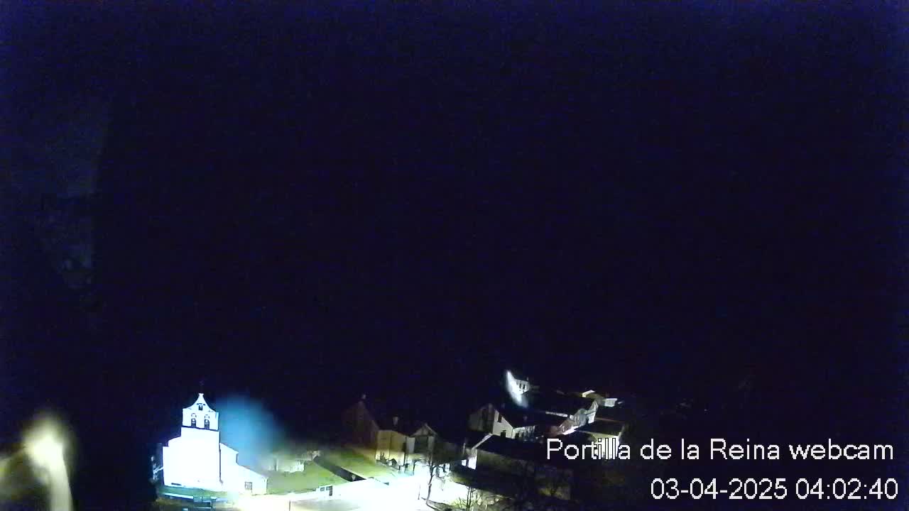 A dimly lit town is visible at night under a dark sky.