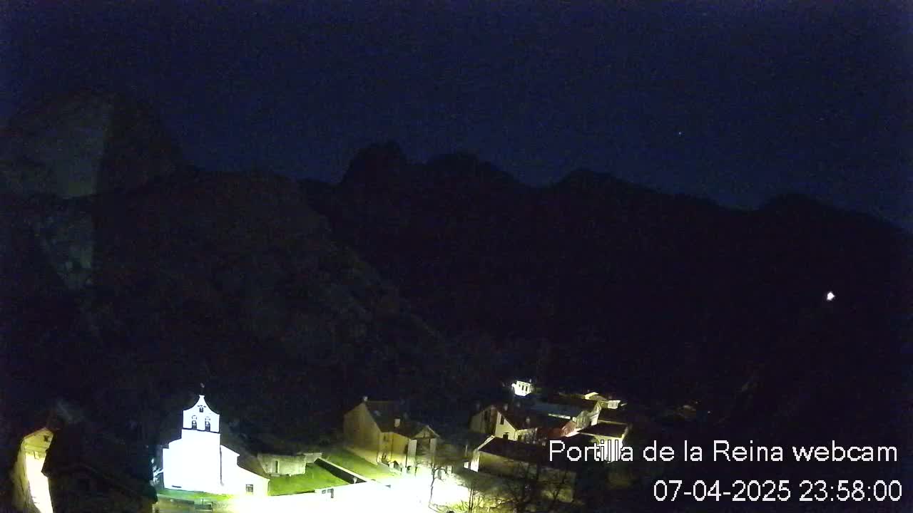 A small village nestled in a dark, mountainous valley at night under a clear sky.