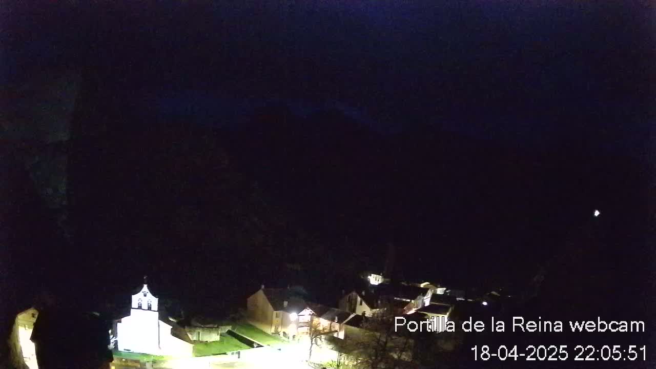 A nighttime view of a small village nestled in a dark valley under a clear, dark sky.