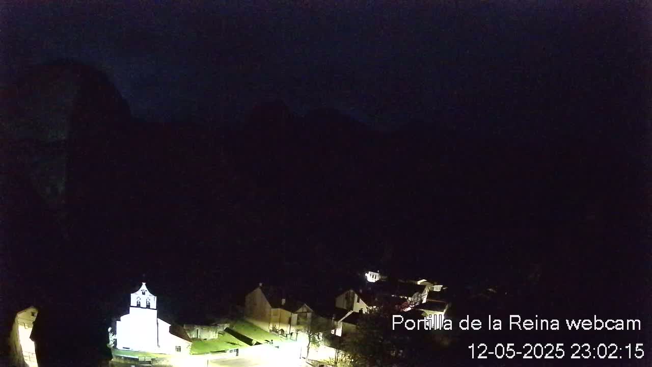 A nighttime view of a small village nestled in a dark, mountainous area.