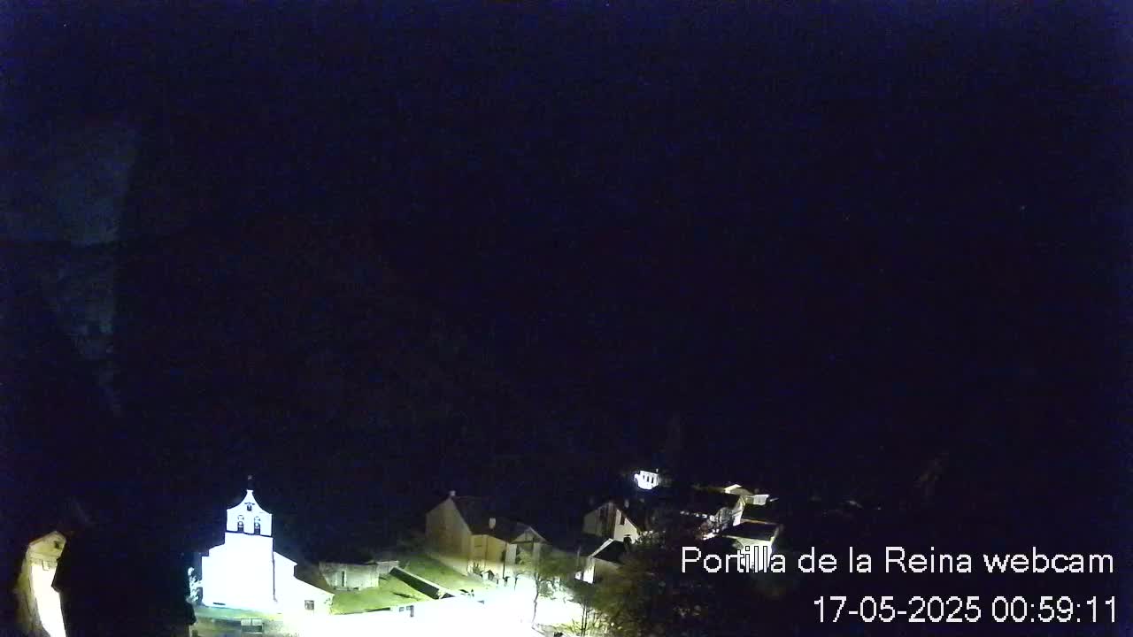A dimly lit, nighttime view of a small village nestled in a dark landscape.