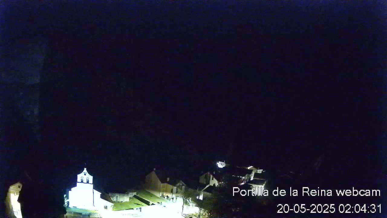 A nighttime, overhead view of a small town with dimly lit buildings, under a dark, clear sky.