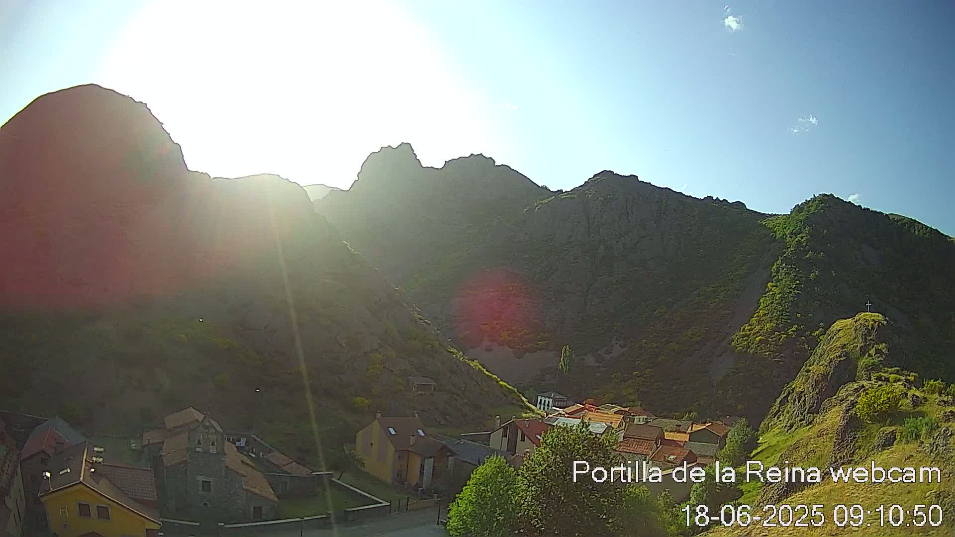 A sunny day reveals a small village nestled in a valley between steep, rocky mountains.
