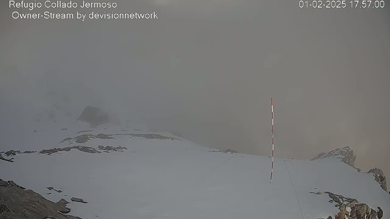 A snow-covered mountain peak is shrouded in thick fog.