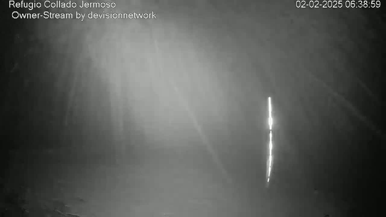 A bright vertical light source is visible in the distance through a hazy, dark nighttime atmosphere.