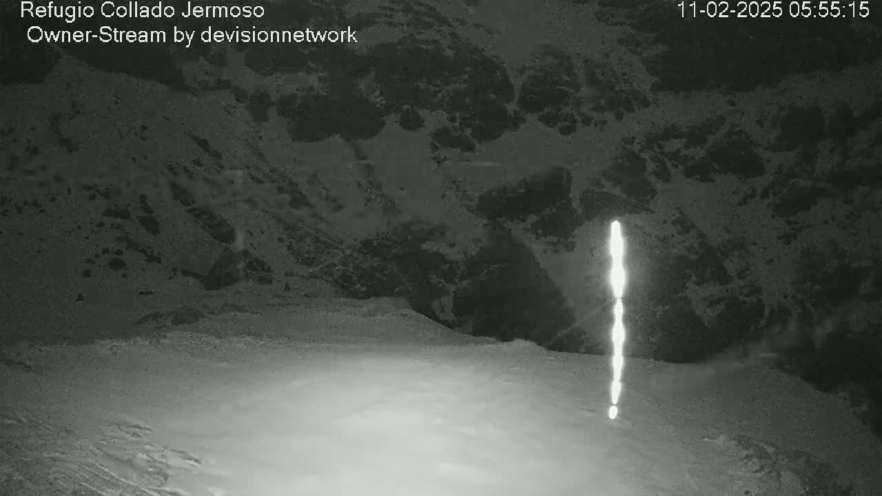 A bright, vertical light streaks across a snowy, dark landscape at night.