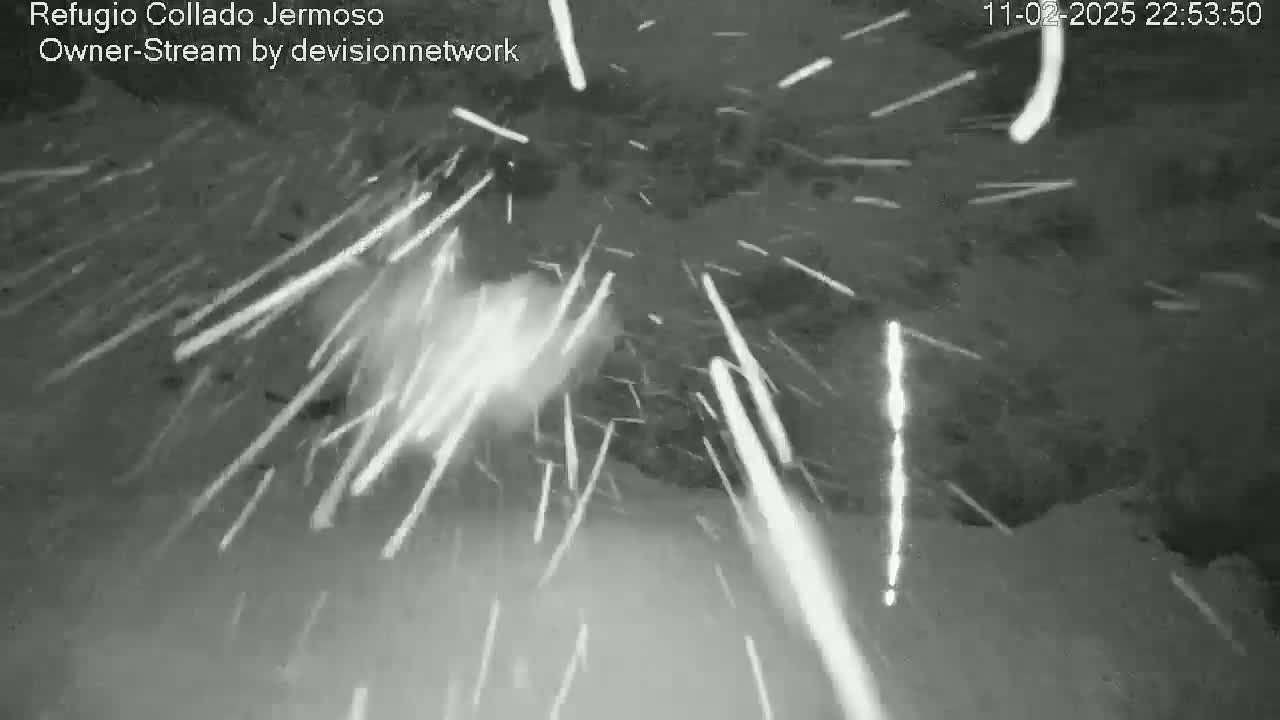 A nighttime, snowy scene is shown with streaks of light appearing to fall from the sky.