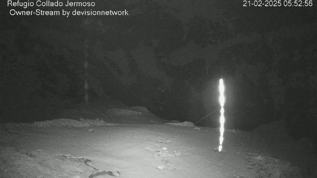 A nighttime, snow-covered landscape is illuminated by a vertical string of bright lights.