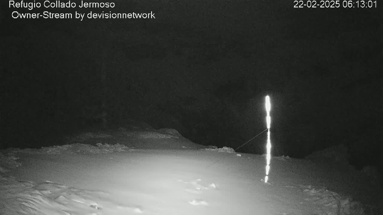 A tall, bright vertical line stands in a snow-covered landscape at night.