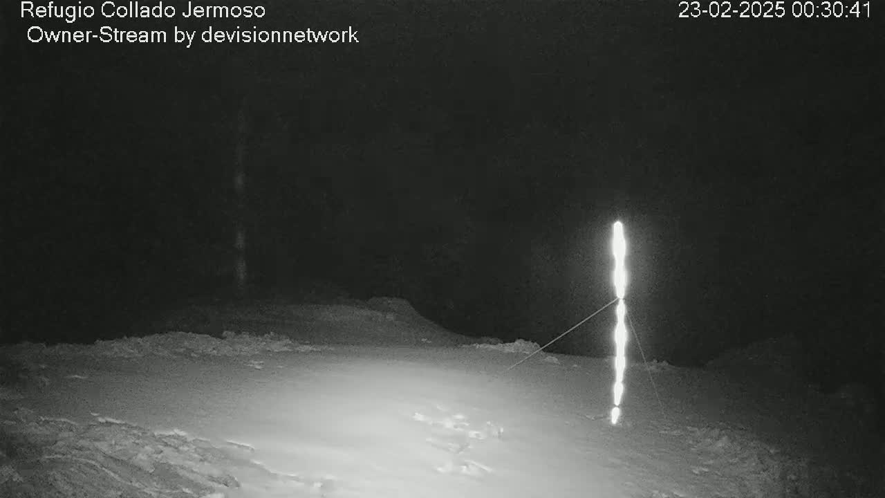 A bright, vertical light source stands in a snow-covered landscape at night.