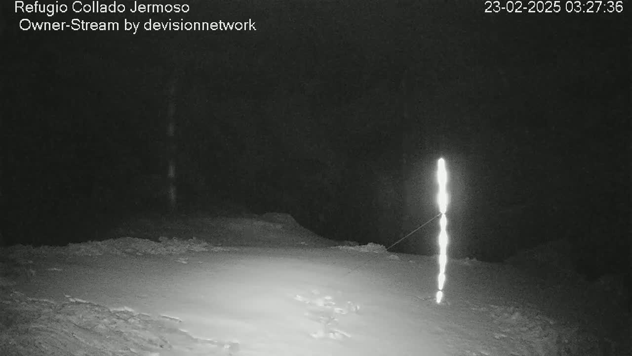 A bright, vertical light source stands in a snow-covered landscape at night.