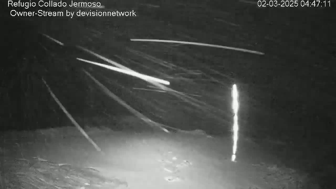A nighttime, outdoor image shows numerous bright streaks of light across a dark sky, suggesting a meteor shower.
