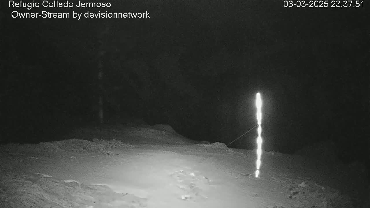 A snow-covered ground at night is illuminated by a tall, vertical light source.