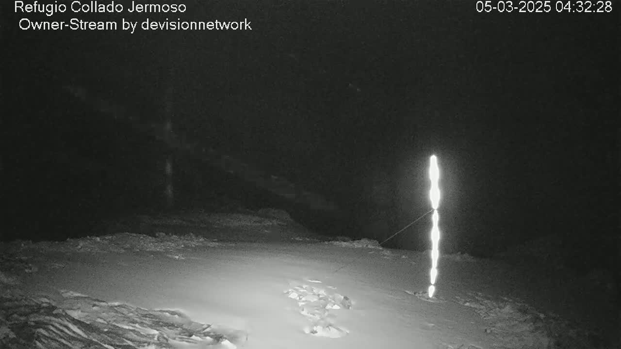 A tall, bright light illuminates a snow-covered ground at night.