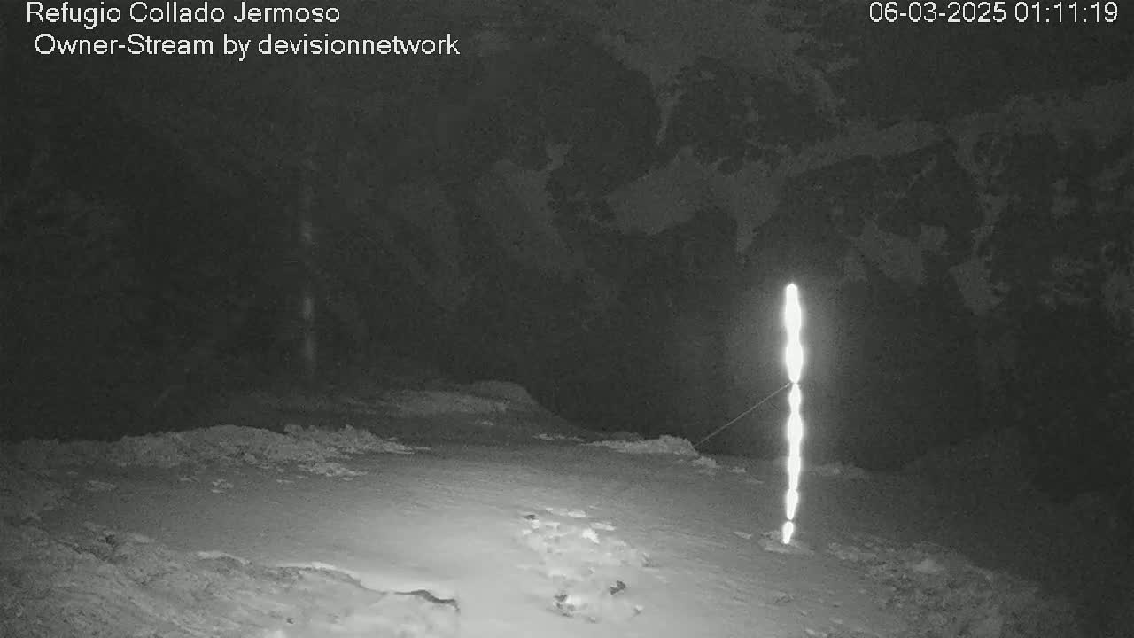 A tall, bright light source stands in a snowy, dark landscape at night.