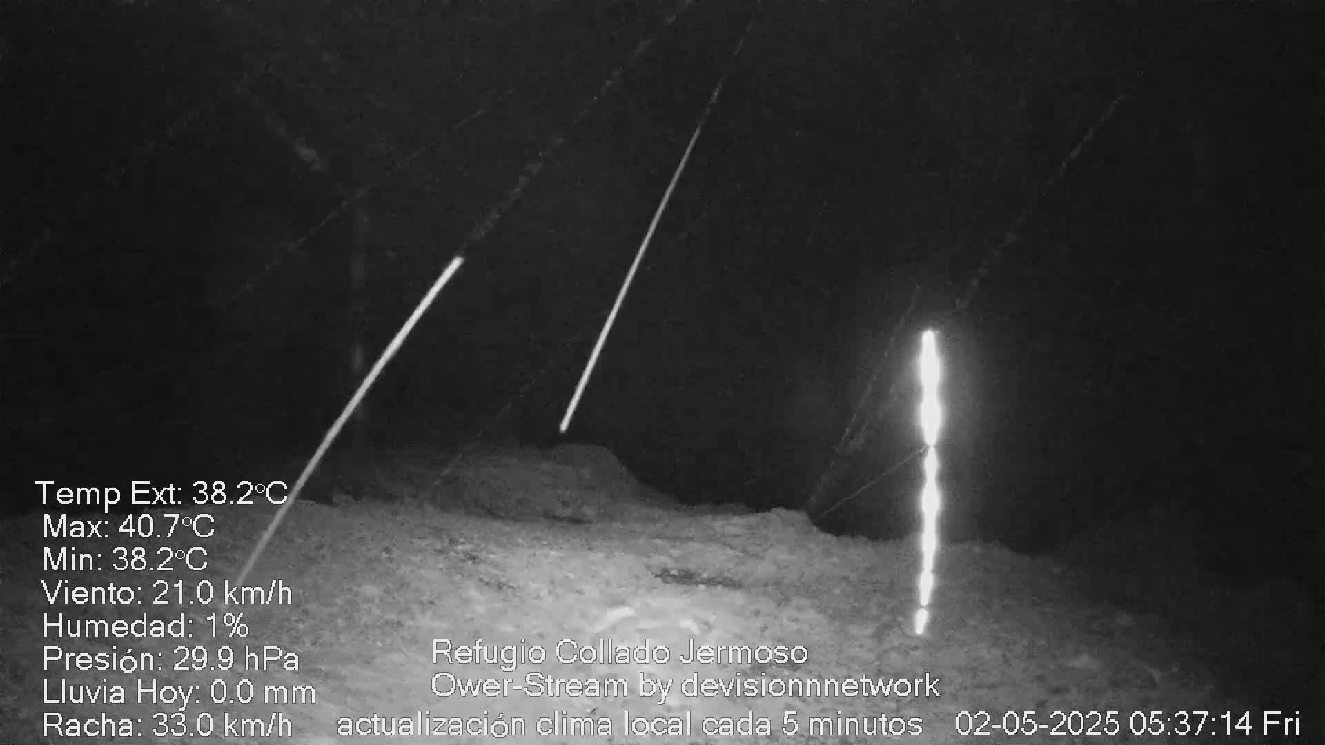 At night, under a clear sky with a 21 km/h wind, bright lights illuminate a dark, rocky landscape.