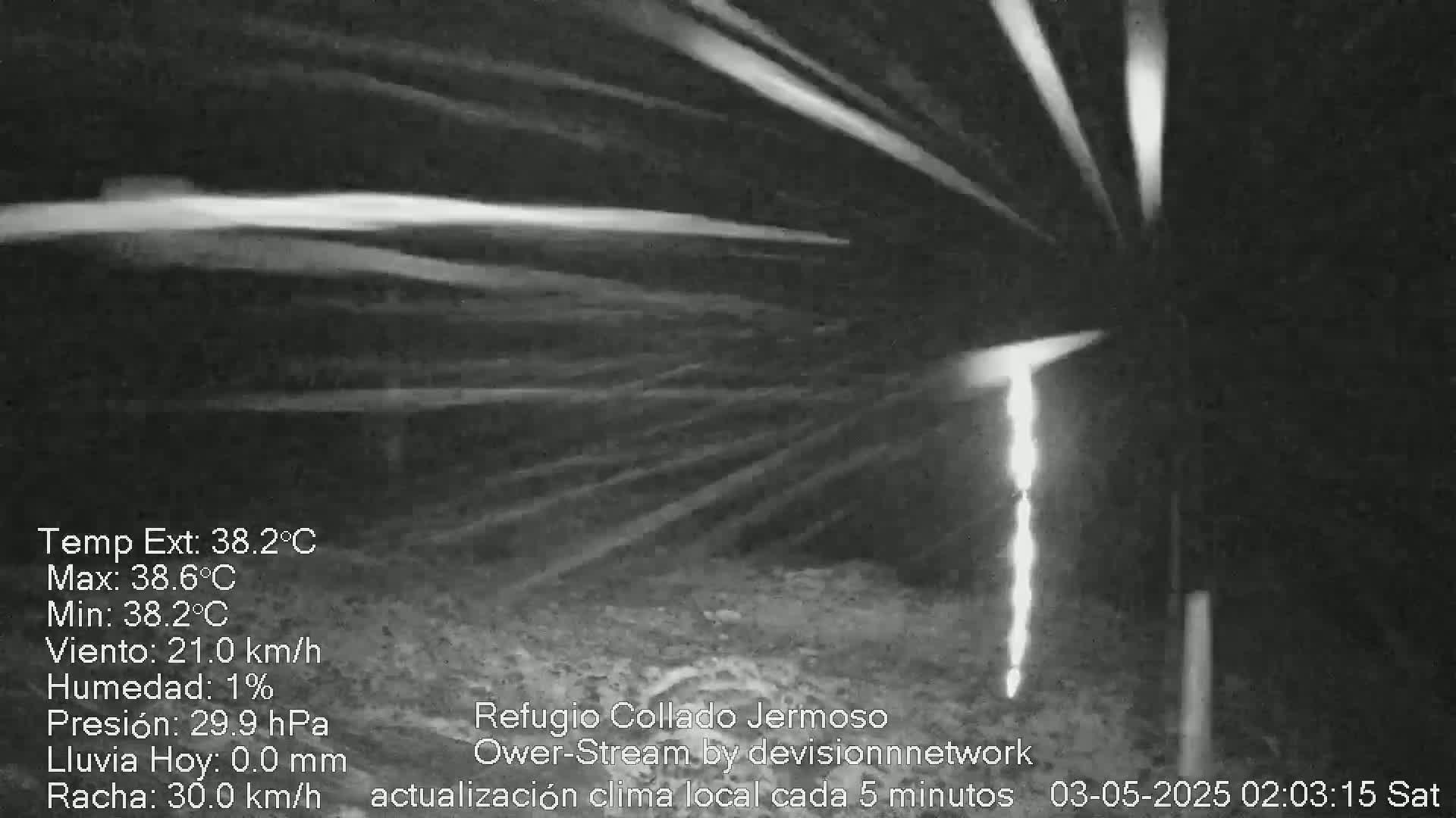 A bright, vertical light source is visible at night in a dark, possibly mountainous, area with a strong wind.